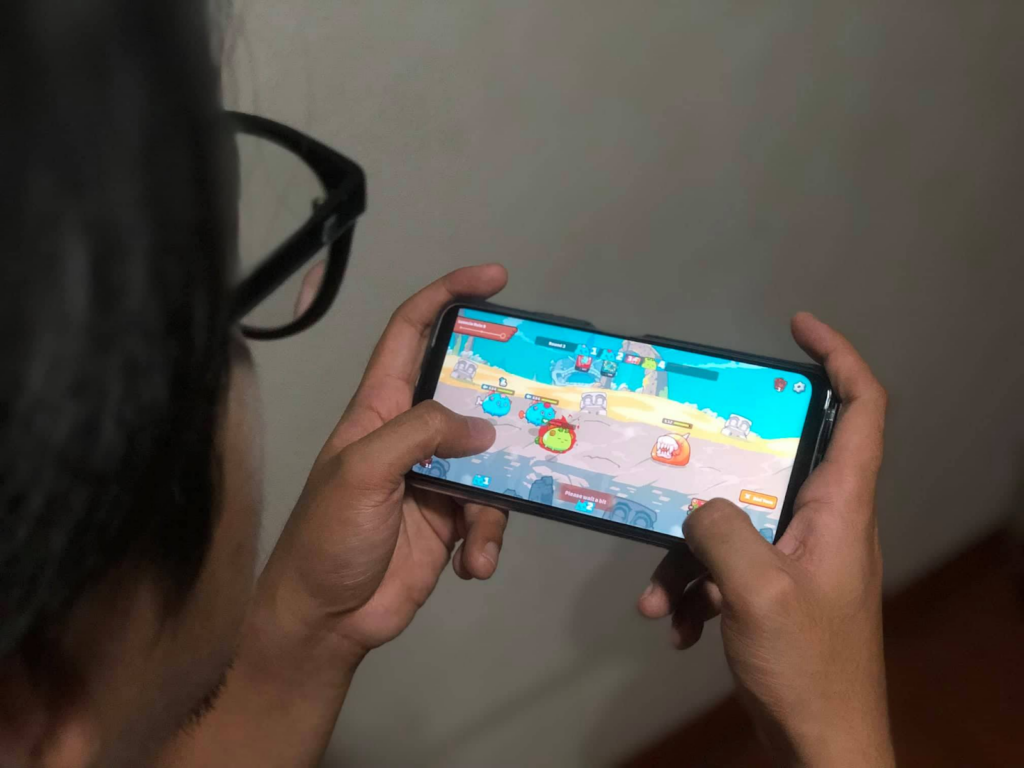 boy playing axie game on mobile